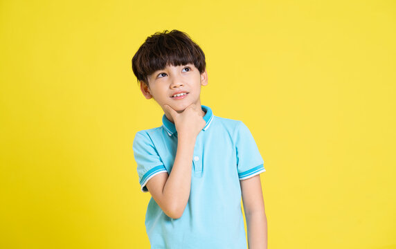 portrait of an asian boy posing on a yellow background