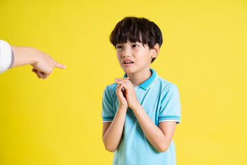 portrait of an asian boy posing on a yellow background
