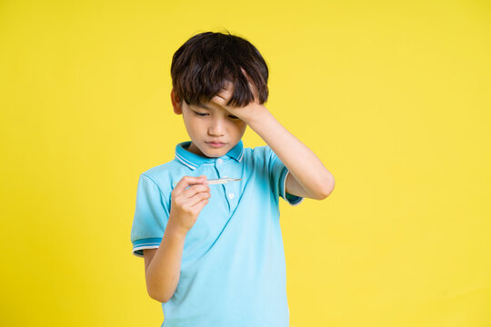 portrait of an asian boy posing on a yellow background