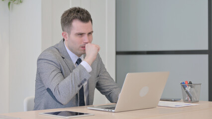 Young Businessman Coughing while Working on Laptop