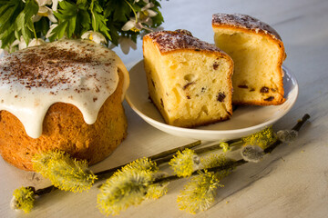 Easter cake on a plate. Easter sweet bread and spring flowers in a sun shine, orthodox easter. Traditional food, religious. Homemade bakery.