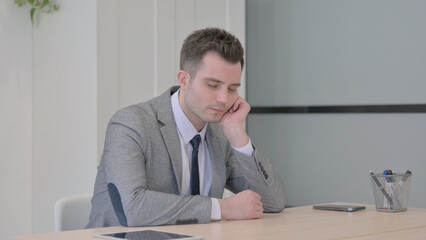 Young Businessman Sleeping while Sitting at Work