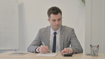 Young Businessman Working on Documents, Calculating and Counting Dollar