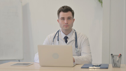 Young Doctor Looking at Camera while using Laptop