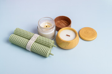 Handmade candles of different types on blue background. Beeswax candles, candle in glass and plaster cup