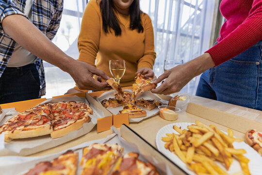 Group of employees eating Italian pizza Hand picked pizza in a lunch or dinner shop. Tasty seafood gravy sauce. Traditional Italian fast food on wooden table with drinking wine.
