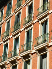 Obraz premium Windows with shutters and small balconies outside on the building facade downtown Madrid, Spain. Vertical photo