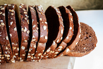 Healthy sliced bread on rustic wooden board, seed bread source of energy, carbohydrates and fiber, traditional flavor.