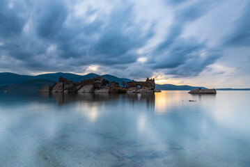 Obraz premium Different views of Bafa Lake in Aegean province of Turkey, boats pier island with monastery and rock forms on a colorful sunset and reflections