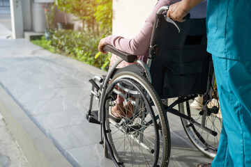 Caregiver help and care Asian senior or elderly old lady woman patient sitting on wheelchair to ramp in nursing hospital, healthy strong medical concept.