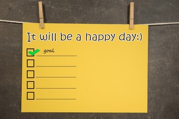 napis "It will be a happy day" na wiszącej żółtek kartce.  Koncepcja planowania i realizacji celów.