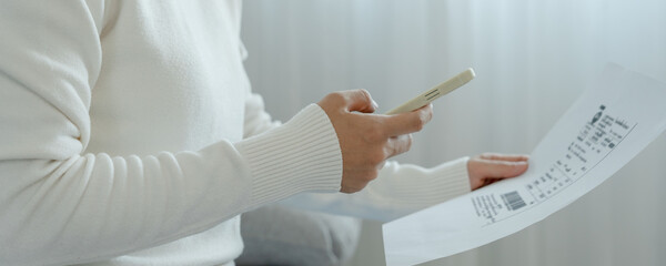 woman use phone scan barcode or QR codes to pay credit card bill after receiving document invoice....