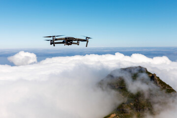 Fototapeta na wymiar Drone with camera flying over the mountain peak and white clouds.