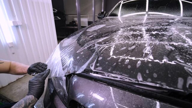 Man covering car with vinyl polyurethane tape. Films for the car. Sticker protective film on the car