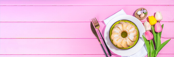 Traditional Easter round bundt cake. Sweet traditional Easter baking with sugar powder sprinkles, colorful Easter eggs, spring flowers, on pink yellow colorful background copy space