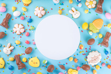 Easter sweets and candies background. High-colored blue flat lay with various Easter chocolate...