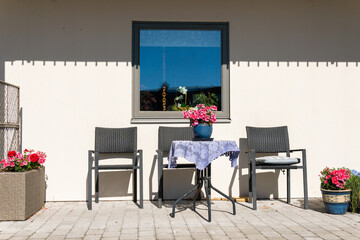 Chairs and table for relaxing outdoors on the terrace, veranda. Comfort relaxing zone. Recreational area. Cozy and comfortable atmosphere. Sunny day. A pot with flowers on the table. 