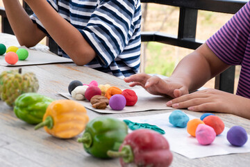 Asian boys spending free time with modeling clays at home by molding plasticine into the shapes of animals, fruits and other things at home, in motion.