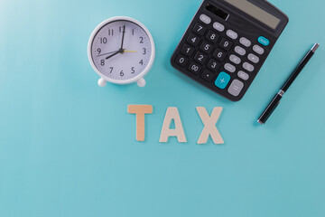 Tax concept - 'Tax' word, clock, pen and calculator  with on blue or green backgound color