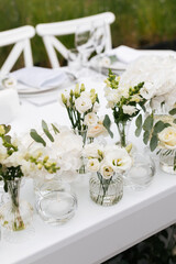 Close up of a wedding table decoration with vases of white flowers and eucalyptus. Wedding outdoor and floristic concept 