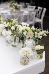 Close up of a wedding table decoration with vases of white flowers and eucalyptus. Wedding outdoor and floristic concept 