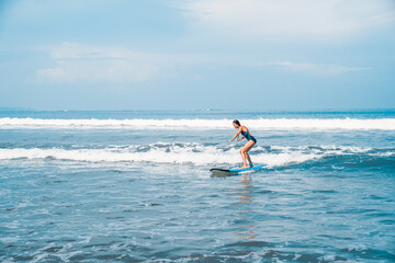 The man is surfing. A novice surfer on the waves in the ocean off the coast of Asia on the island of Bali in Indonesia.