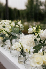 Close up of a wedding table decoration with vases of white flowers and eucalyptus. Wedding outdoor and floristic concept 