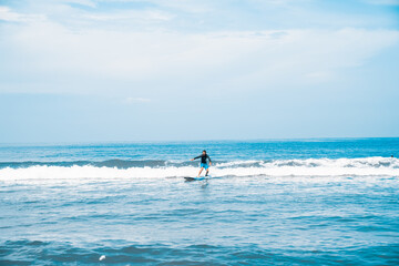 Fototapeta na wymiar The man is surfing. A novice surfer on the waves in the ocean off the coast of Asia on the island of Bali in Indonesia.