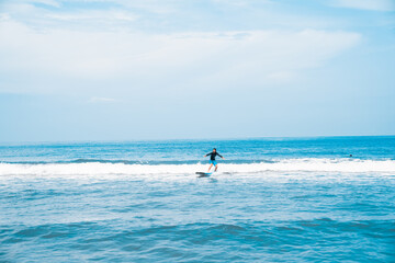Fototapeta na wymiar The man is surfing. A novice surfer on the waves in the ocean off the coast of Asia on the island of Bali in Indonesia.