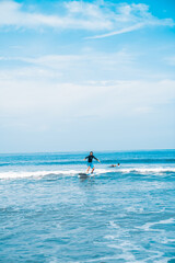 Naklejka premium The man is surfing. A novice surfer on the waves in the ocean off the coast of Asia on the island of Bali in Indonesia.