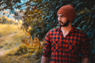 lumberjack man in cap walking in nature with red plaid lumberjack shirt