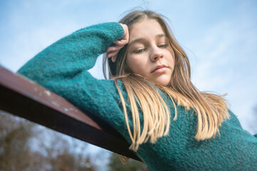 Sad teen girl on a bench in the park. Single girl on a bench.