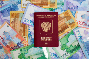 Top view. Background from paper Kazakh banknotes. Red biometric Russian passport. Concept of immigration, relocation, tourism to Republic of Kazakhstan. 10000 tenge. Cash for travel. Currency exchange