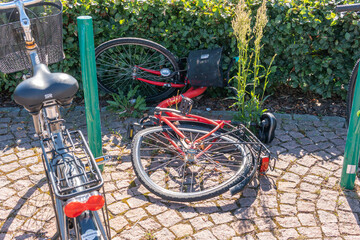 Sweden, Knislinge – August 24, 2022: A broken abandoned bicycle with bent wheel parked outdoors laying on the ground. Symbol of street vandalism. 