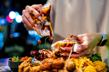 hungry woman hand holding and eatting fried chicken meat in pub