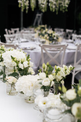 Fototapeta premium Close up of a wedding table decoration with vases of white flowers and eucalyptus. Wedding outdoor and floristic concept 