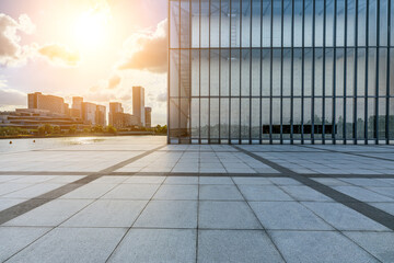 Empty square floor and glass wall building with the city skyline in Ningbo at sunset, Zhejiang...