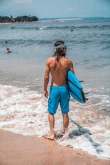 The man is surfing. A surfer on the waves in the ocean off the coast of Asia on the island of Bali in Indonesia. Sports and extreme. Beauty and health. Fashion and beach style.
