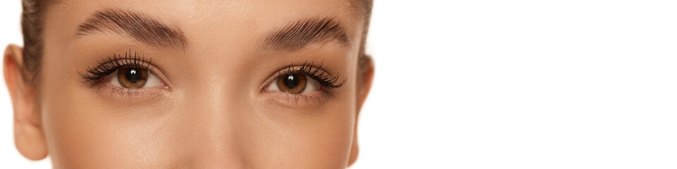 Obraz premium Cropped image of beautiful female face, eyes over grey background. Natural makeup look. Brows and lashes lamination. Concept of cosmetology, cosmetics, natural beauty. Banner, flyer. Copy space for ad