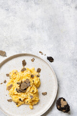 Scrambled eggs with fresh black truffles from Italy served in a plate top view, gourmet breakfast