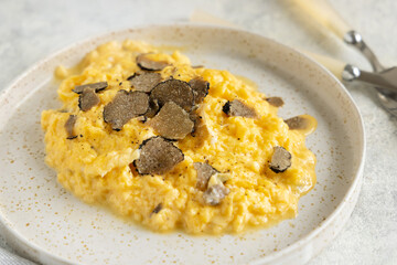 Scrambled eggs with fresh black truffles from Italy served in a plate close up, gourmet breakfast