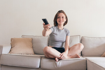 Cheerful woman with remote controller on sofa