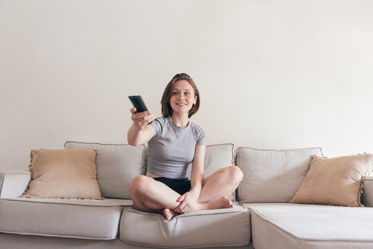 Cheerful woman with remote controller on sofa