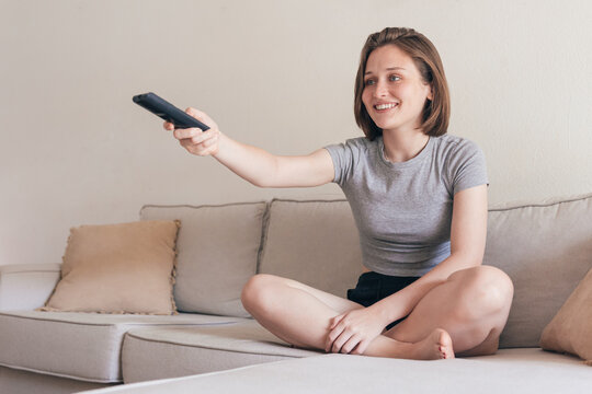Cheerful woman with remote controller on sofa