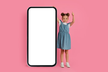 Cute Little Girl Standing Near Big Blank Smartphone And Showing Thumb Up