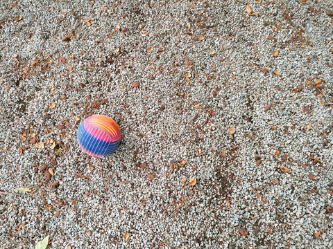 Un pavimento de grava con una pelota de colores