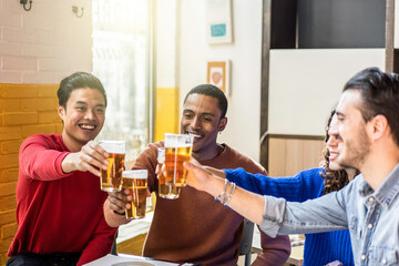 Happy friends drinking beer at pub bar - Multiracial lifestyle concept with genuine people enjoying...