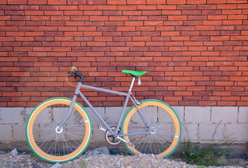 a yellow-green bicycle is parked near a red-brown brick wall, texture backround