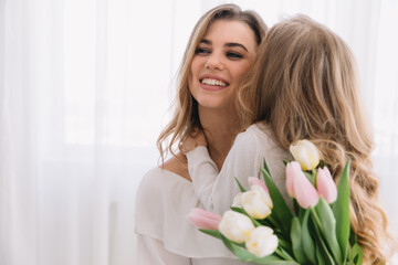 Happy mother's day. Child daughter congratulates moms and gives her flowers tulips.