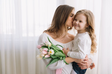 Happy mother's day. Child daughter congratulates moms and gives her flowers tulips.